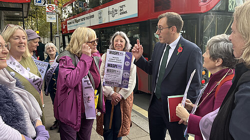 Tom Gordon on the street near Parliament talking to WASPI women in front of a London bus