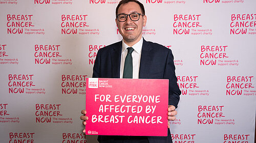 Tom Gordon MP holding a sign reading 'For everyone affected by Breast Cancer'