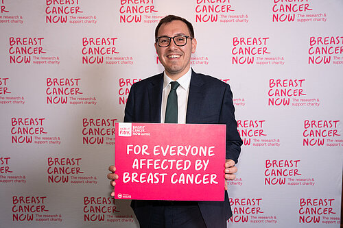 Tom Gordon MP holding a sign reading 'For everyone affected by Breast Cancer'