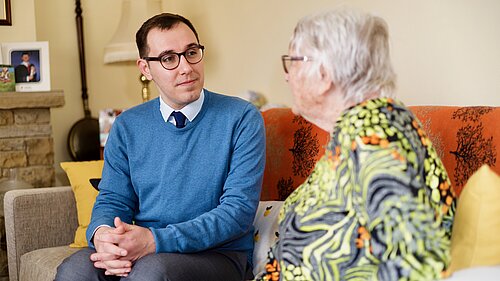 Tom Gordon sat on a sofa with a pensioner