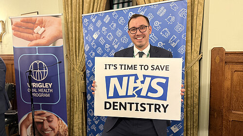 Tom Gordon stood with a sign reading 'It's time to save NHS Dentistry'