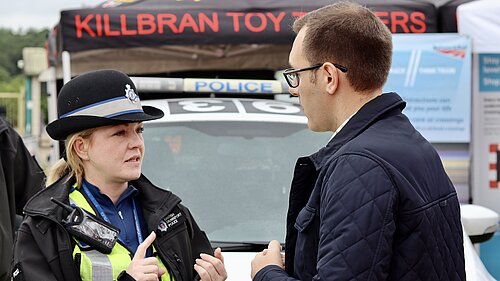 Tom Gordon speaking to a policewoman in front of a police van